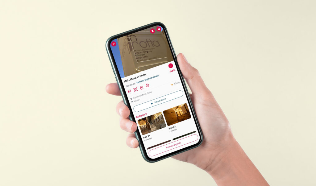 Una donna tiene in mano uno smartphone in cui è visibile l'app gratuita per l'audiotour del MiG-Musei In Grotta