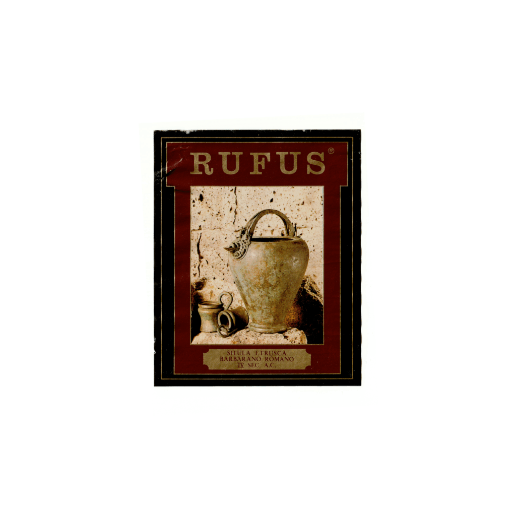 Il vino rosso Rufus, prodotto a Montefiascone, in Italia, presenta un'etichetta rettangolare realizzata in carta patinata lucida e stampata con tecnologia Offset.